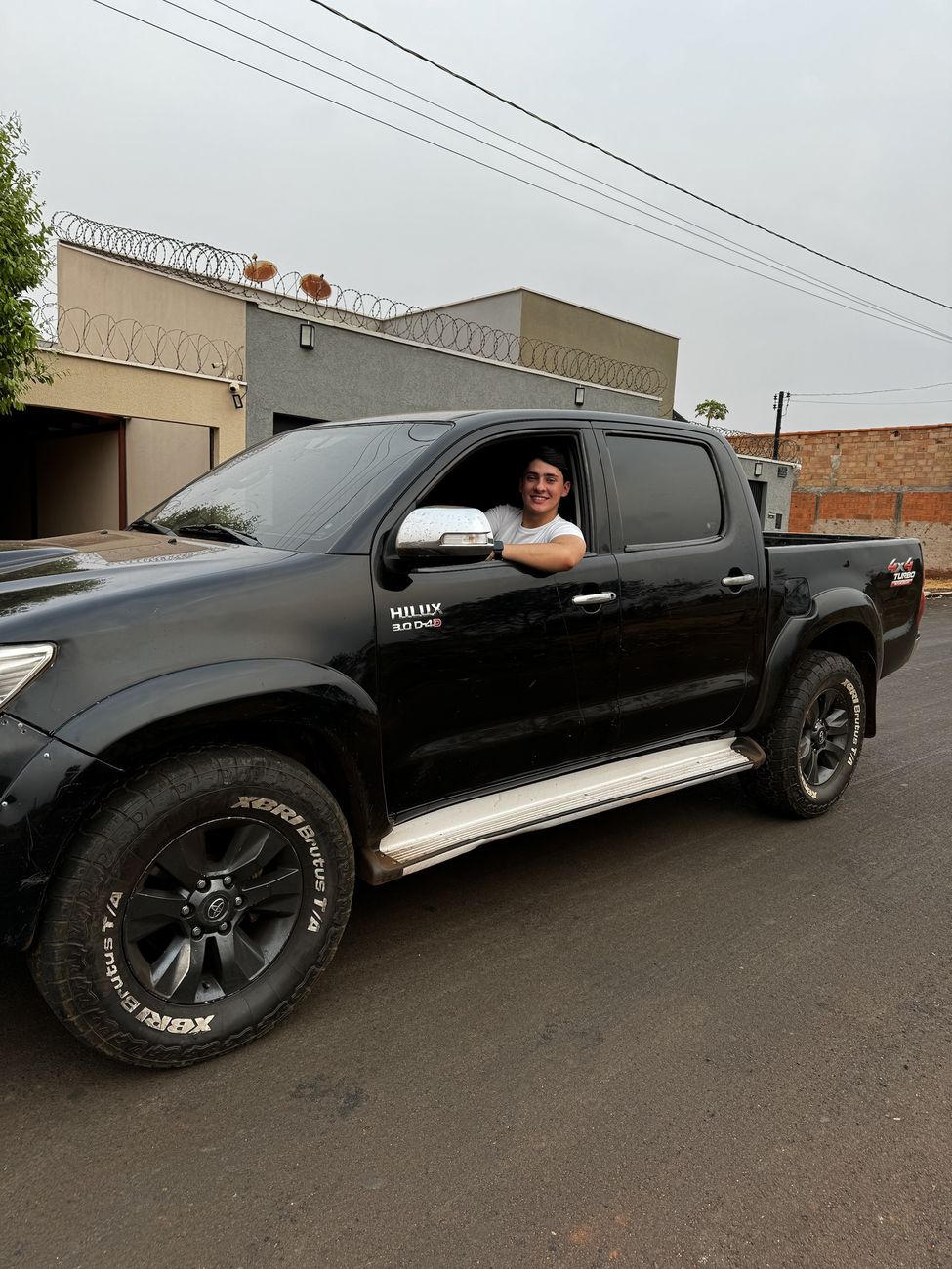 Wallas sorrindo na janela de uma Hilux preta